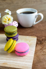 Colorful macaroons and a cup of coffee on wooden table