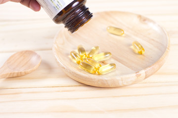 Obraz na płótnie Canvas Closeup soft gelatin supplement fish oil capsule on wooden