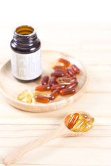 Closeup soft gelatin supplement fish oil capsule on wooden