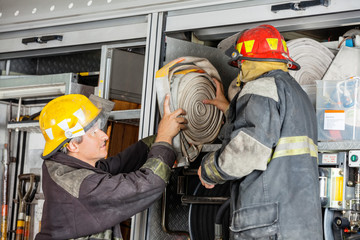 Naklejka premium Firefighters Removing Water Hose From Truck