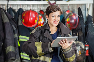 Obraz premium Happy Firewoman Holding Digital Tablet At Fire Station