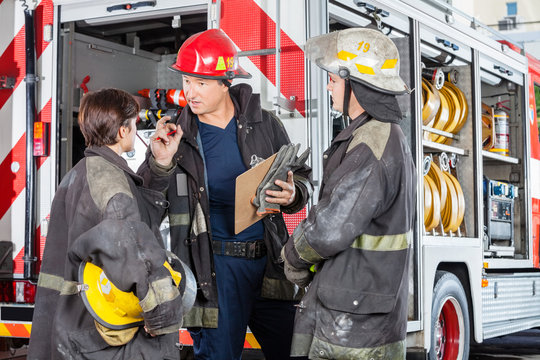 Firefighter Discussing With Colleagues Against Truck