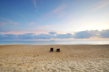 The beach chairs on sand beach during sunrise or sunset