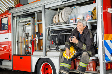 Obraz premium Happy Fireman Sitting In Truck At Fire Station