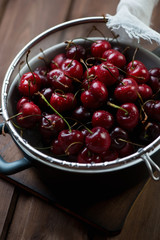 Colander with fresh sweet cherries, close-up, selective focus
