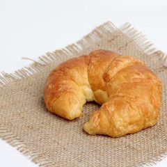 one croissant on spuare frayed burlap