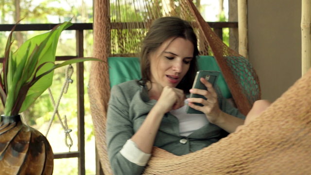 Young businesswoman using smartphone while lying on hammock 
