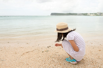 南国の砂浜で貝殻をひろう少女