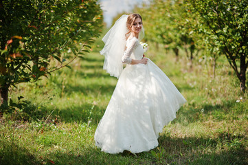 Obraz na płótnie Canvas Gentle bride walking at apple garden