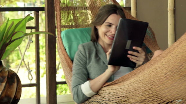 Young businesswoman working with tablet computer while lying on hammock
