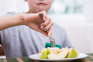 Displeased boy eating apple