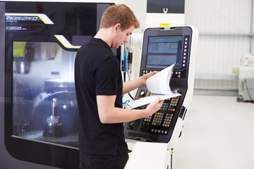 Male Engineer Operating CNC Machinery On Factory Floor