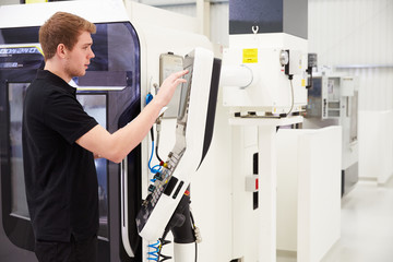 Male Engineer Operating CNC Machinery On Factory Floor