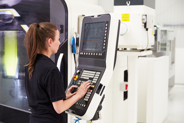 Female Engineer Operating CNC Machinery On Factory Floor