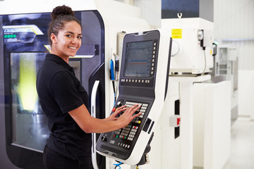 Female Engineer Operating CNC Machinery On Factory Floor