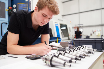 Engineer Planning Project With CNC Machinery In Background
