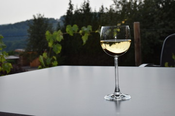Weißwein im Glas, auf grauem Tisch, Hintergrund grün