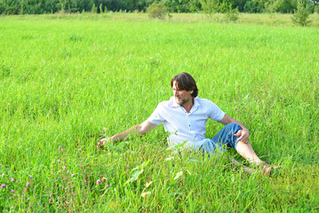  man sits in the grass in the summer