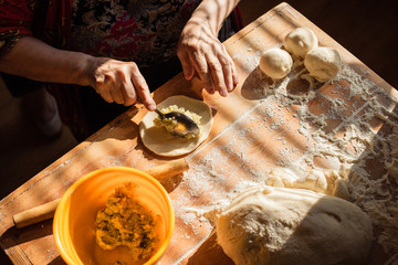 Senior woman prepares pies on a table in her home kitchen