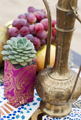 Wedding table arrangement in desert sand of Morocco stile. Fresh grapes near the salver with apples and pears