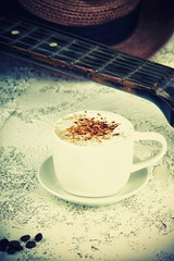 Cappuccino coffee cup and guitar on a table