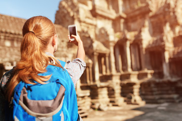 Female tourist with smartphone taking picture of Angkor temple