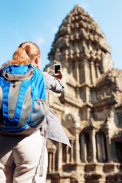 Young female tourist with smartphone in temple Angkor Wat
