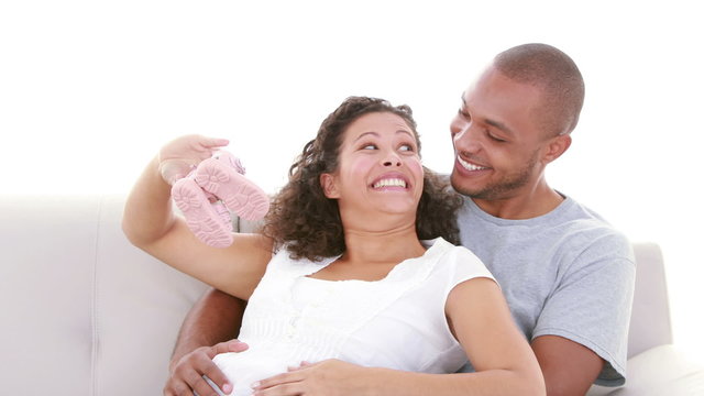 Pregnant woman showing baby shoes on the sofa