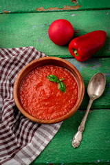 Tomato gazpacho soup on old wooden table.