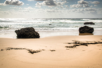 Very rustic and empty beach with large rocks at the Indian Ocean in the coastal town Praia do Tofo in Inhambane, Mozambique
