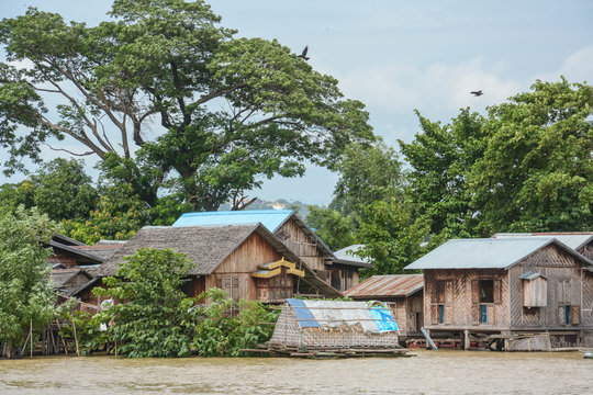 Traditional stilts wooden and bamboo houses and long boats on Ayewadee river in Mandalay, Myanmar (Burma) 