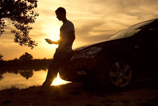 man on the shore of the lake at sunset