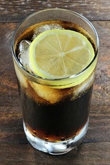 Cola mit Eiswürfeln und Zitronenscheibe auf Holztisch