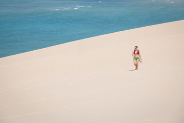 Girl walking on the white dunes on the beach of the Bazaruto Islands near Vilanculos in Mozambique with the Indian ocean in the background
