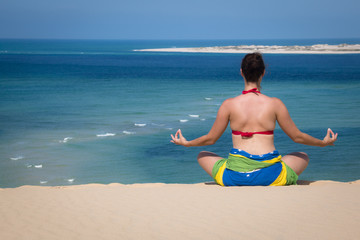 Girl in a sitting yoga pose in the beach of the Bazaruto Islands near Vilanculos in Mozambique with the Indian ocean in the background
