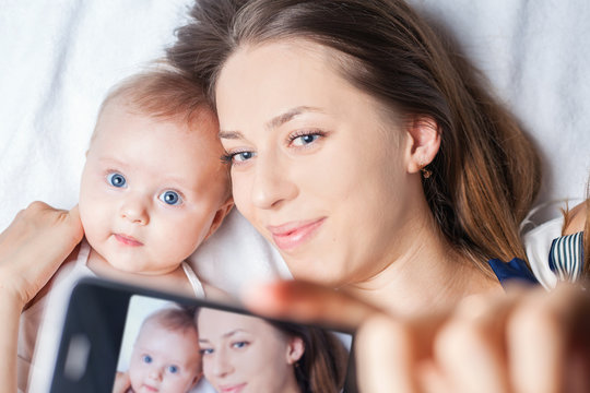 Funny baby girl with mom make selfie on mobile phone