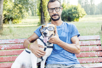 nearsighted man with his dog wearing glasses sitting on a bench - obrazy, fototapety, plakaty