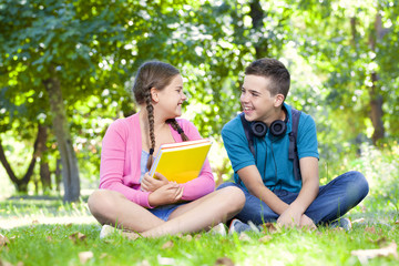 Fototapeta premium Smart kids sitting on the grass looking happy