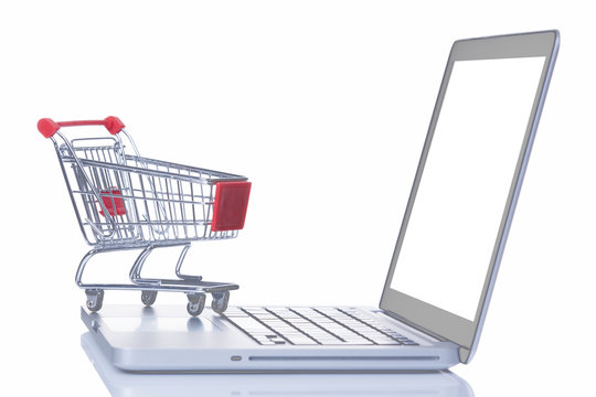 Shopping cart over a laptop computer, isolated on white backgrou