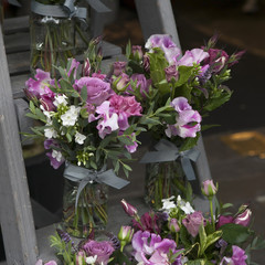 bouquet of Sweet pea, Lathyrus odoratus, flowers in a purple vase standing on wooden grey steps