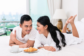 Obraz na płótnie Canvas Asian couple having breakfast in bed