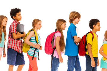 School kids go in line with backpacks profile view