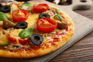 Tasty pizza with vegetables and basil on table close up