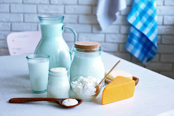 Dairy products on wooden table, on brick wall background