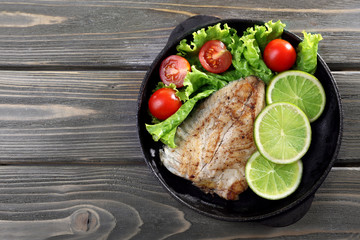 Dish of fish fillet with salad and lime on table close up