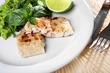 Dish of fish fillet with greens and lime on table close up