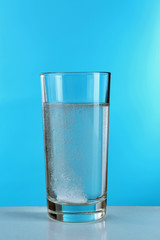 Pill in glass of water on blue background