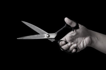 Black and White scissors on hand isolated on black background