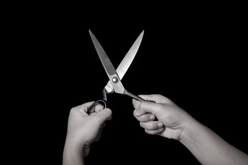 Black and White scissors on hand isolated on black background