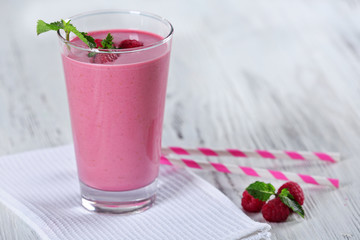 Glass of raspberry milk shake with berries on wooden background